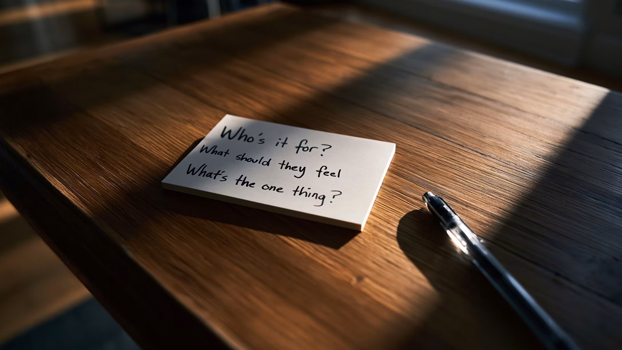 A handwritten index card with three strategy questions on a clean sunlit desk.