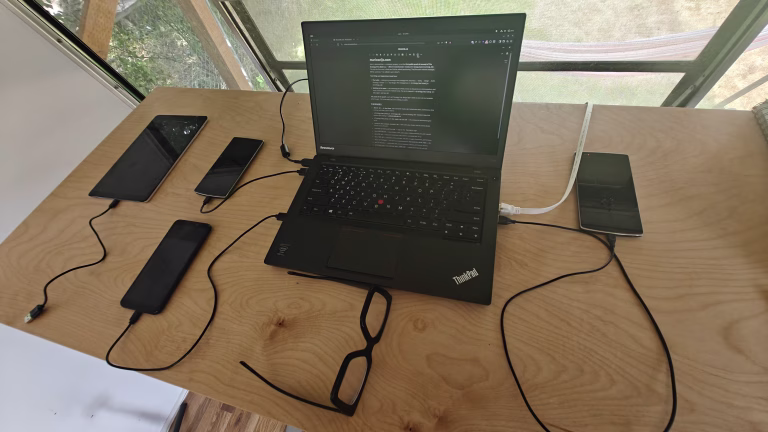 A laptop showing a plain text document beside a blank business card on a sunlit desk.