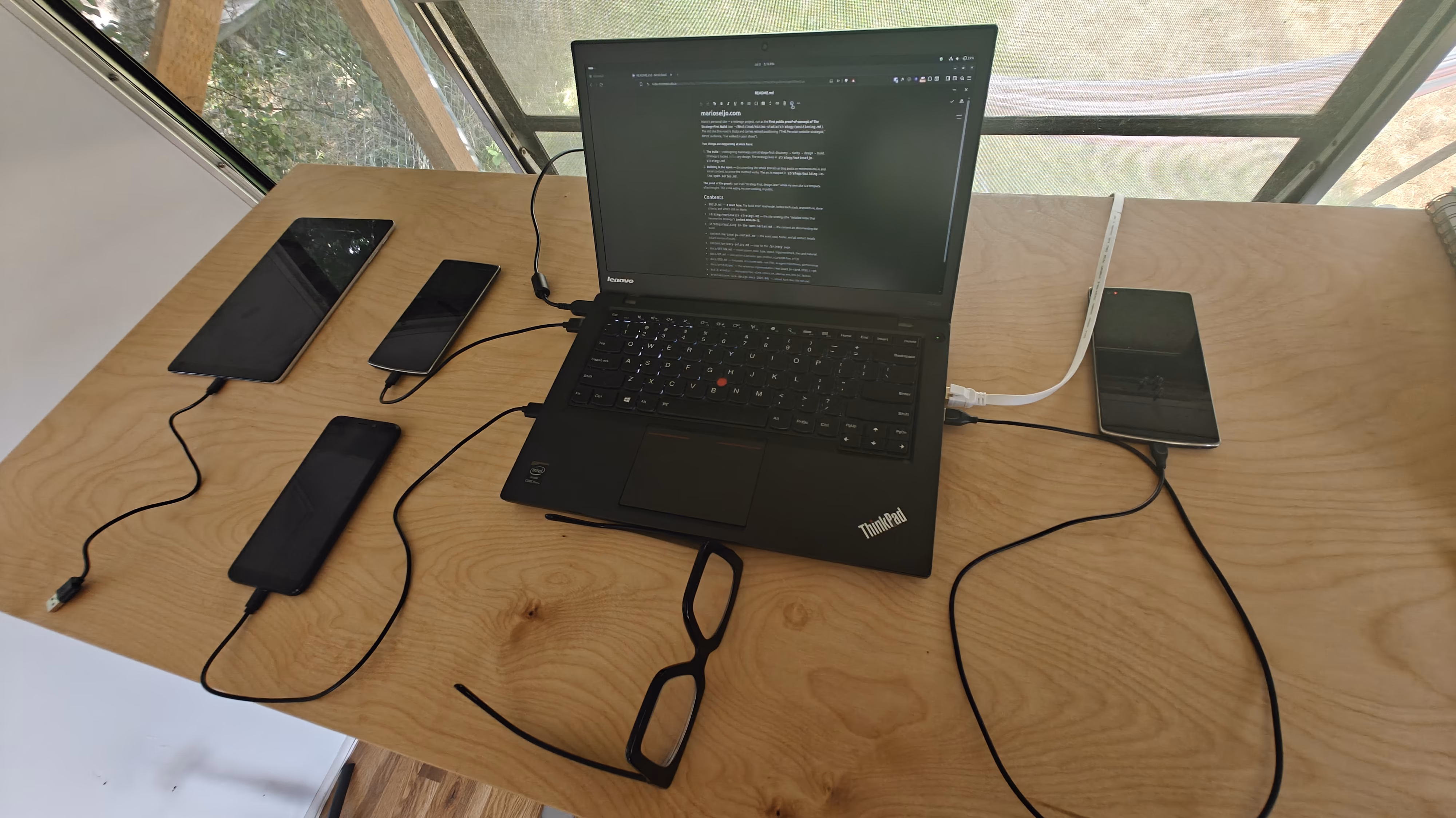 A laptop showing a plain text document beside a blank business card on a sunlit desk.